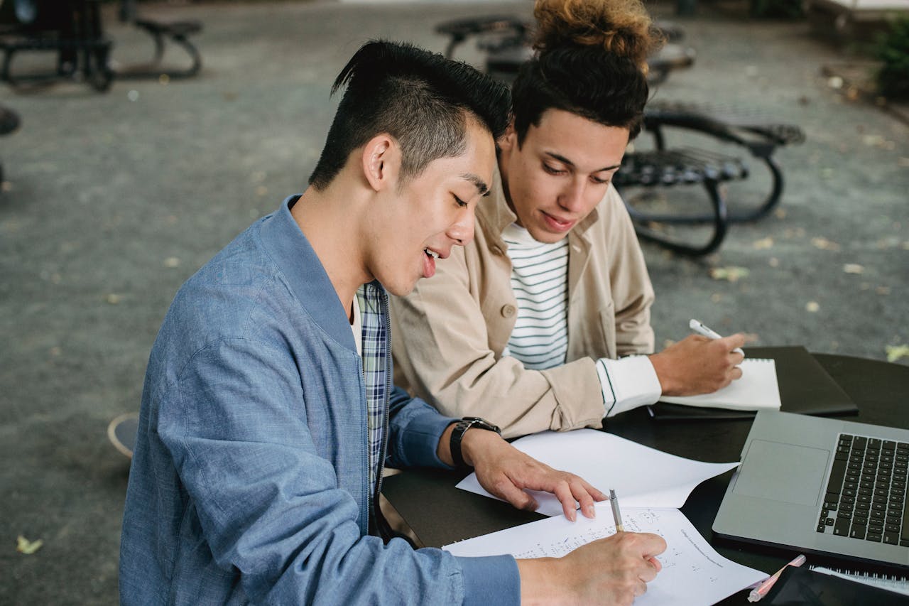 Two students working together on an assignment in a park, engaging in collaborative study.